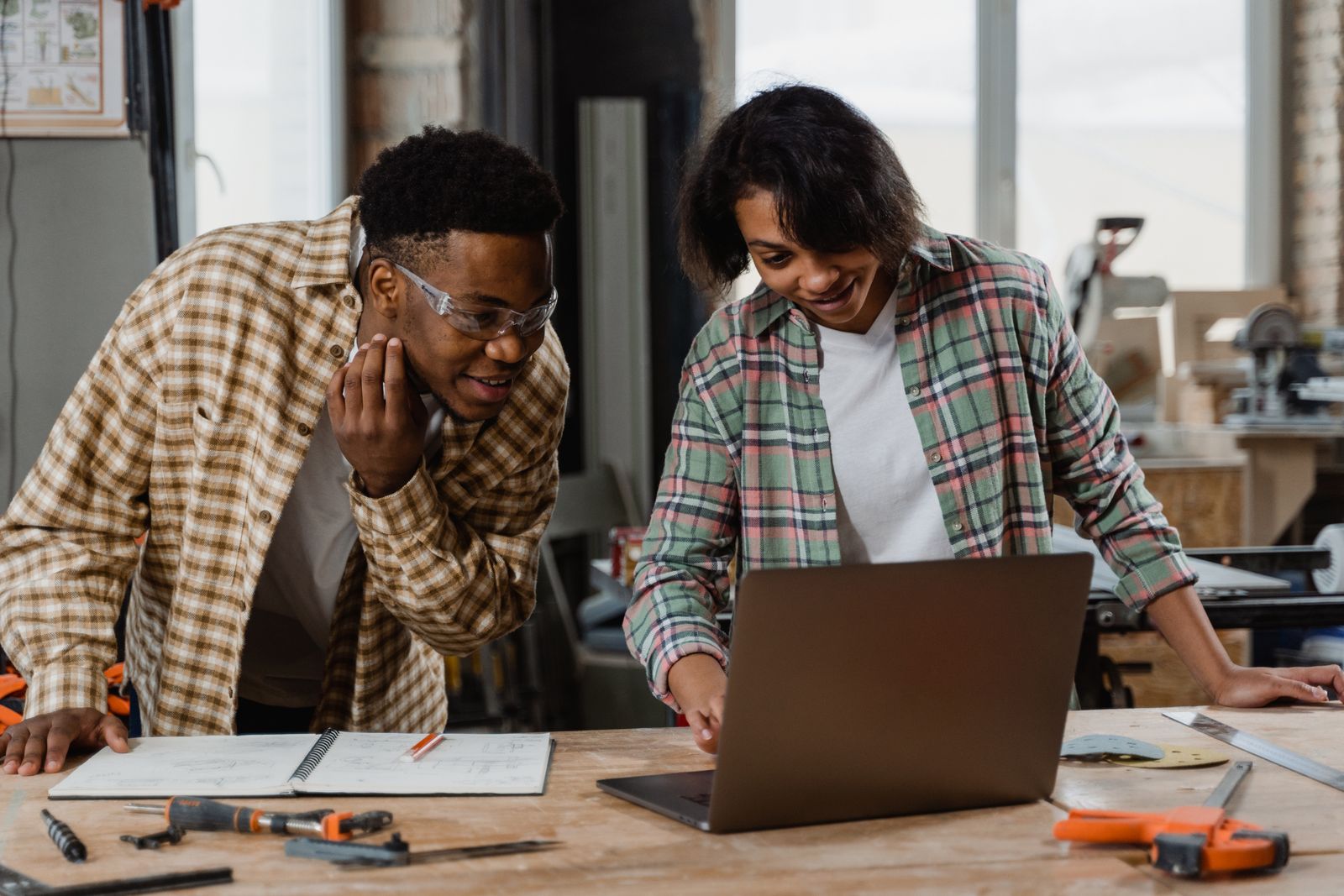 Two people going over numbers on a laptop at a workshop bench